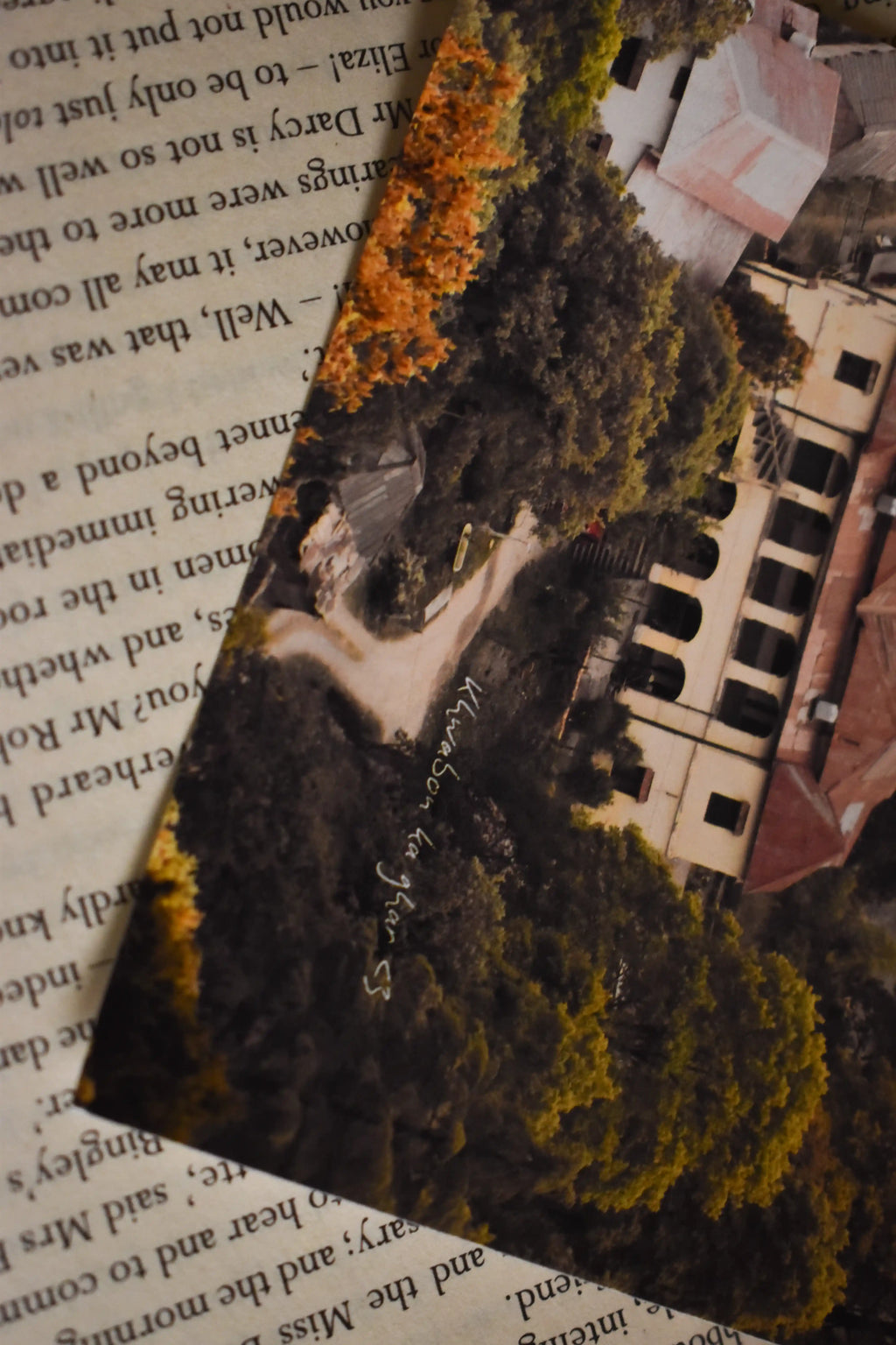 Angled close-up of the 'Khwabon Ka Ghar' Barlowganj Photo Print resting on the text-filled pages of a vintage book, highlighting the colonial estate and handwritten text overlay.