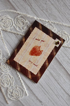 Angled flat lay of the Sunlit Hugs I Miss You Berry Much Greeting Card showing the brown plaid pattern, lace graphic, and strawberry design next to white lace.