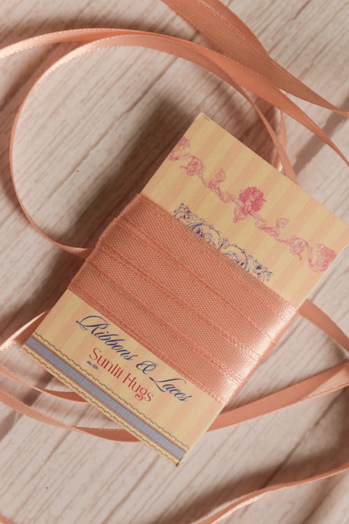 Apricot Satin Ribbon shown with loose satin strands around the product card, highlighting its slim 6 mm width, peach-toned warmth, and soft shine for crafts and gift wrapping.