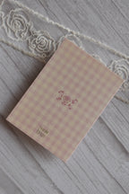 Back cover of the Sunlit Hugs Happy Anniversary Vintage Cake Greeting Card showing the pink gingham pattern, a small rose illustration, and the brand logo.