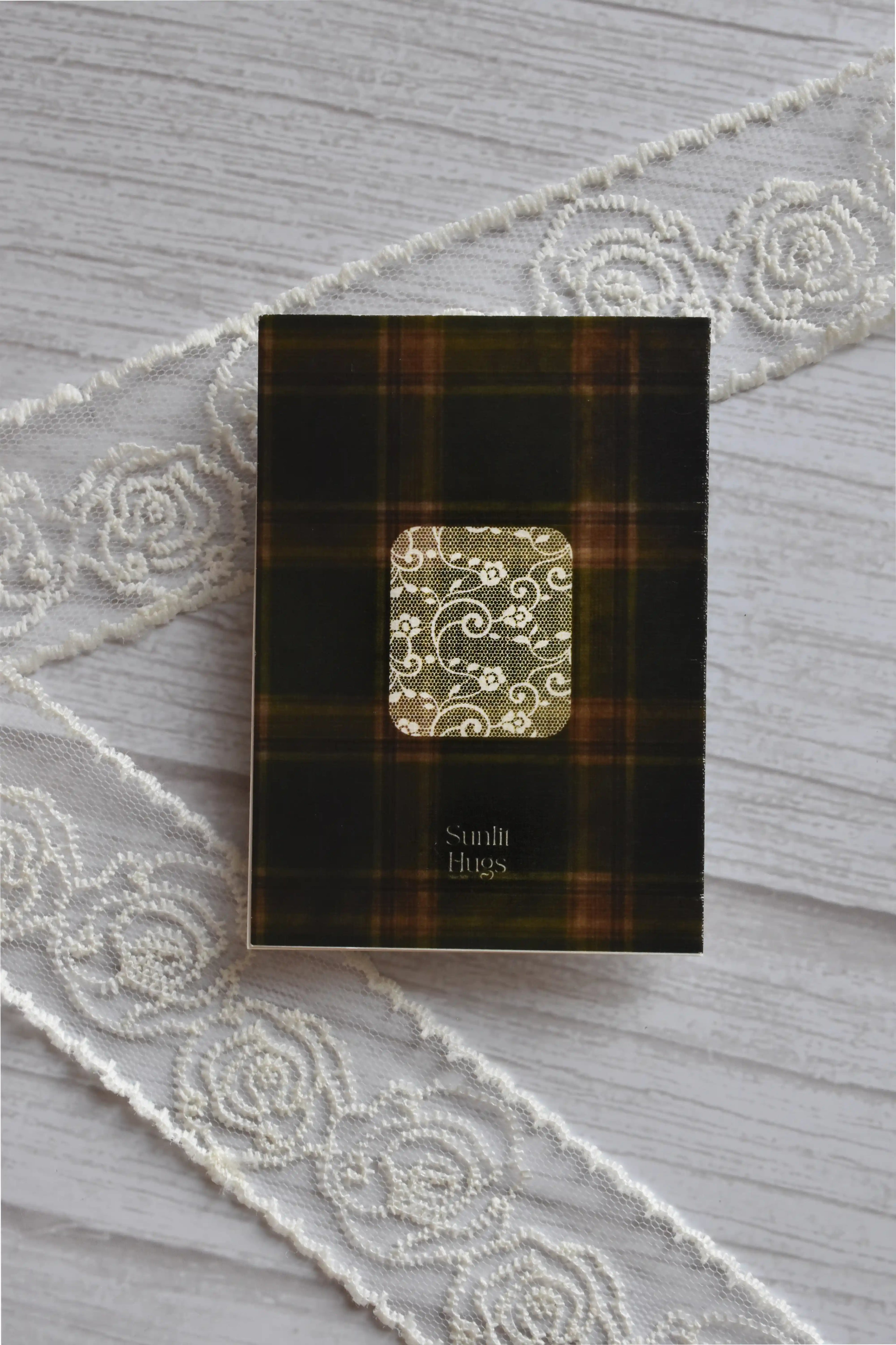 Back cover of the Sunlit Hugs Vintage Plaid Congratulations Greeting Card showing a dark green plaid pattern, a decorative lace square, and the brand logo next to white lace.