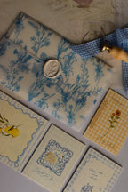 An overhead view of the opened Birthday Sunshine Keepsake Bundle featuring the Midnight Dream Letter, Grateful For You Mini Card, Wishing a 1000 Picnics With You Card, Sending You Birthday Sunshine Card, and Dolce Far Niente Postcard.