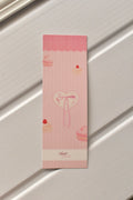 This image shows a detailed, centered view of the Bow Bookmark front, highlighting the soft pastel pink colour and the charming macaron and heart illustration with a delicate bow.