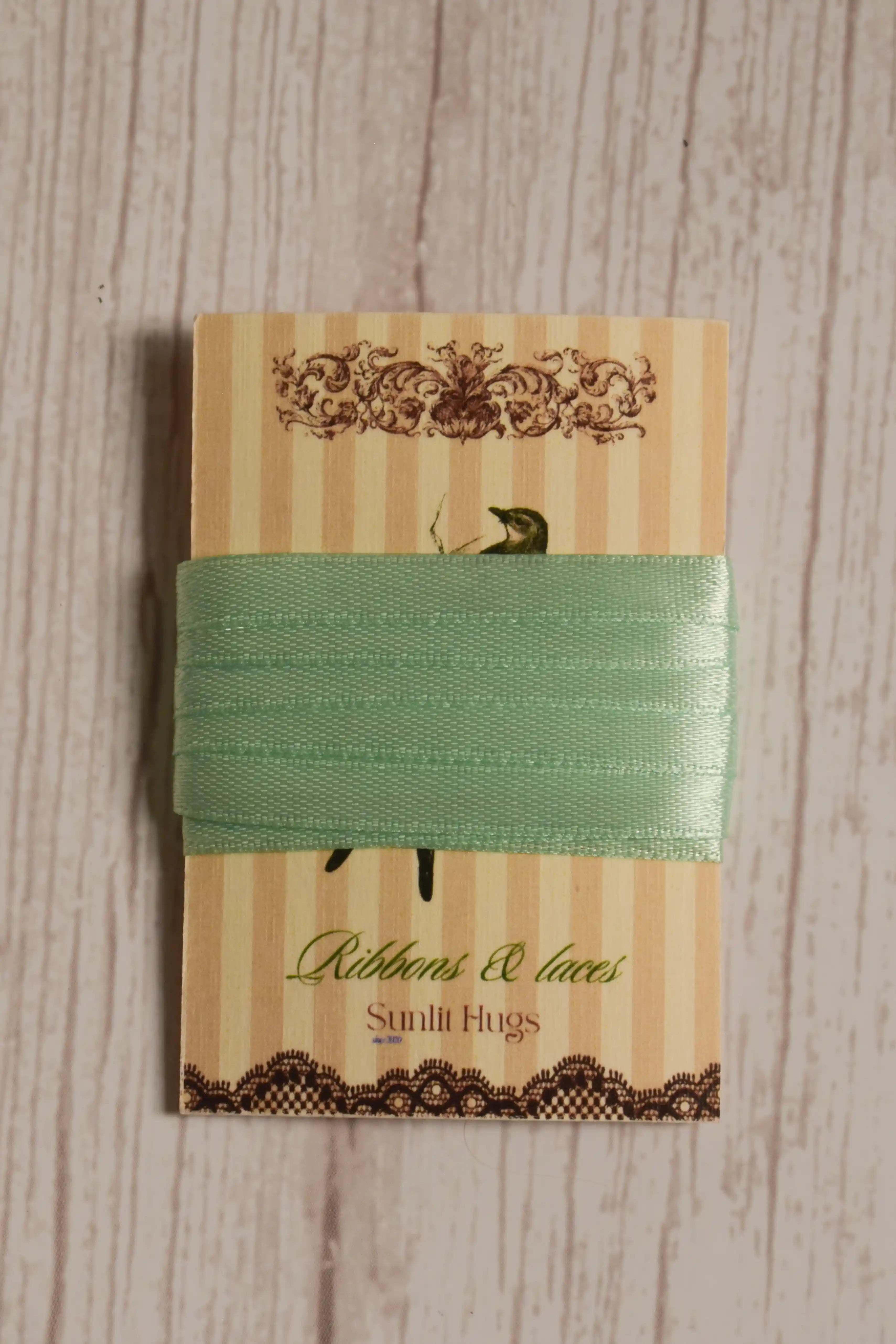 Mint Breeze Ribbon wrapped around a printed Sunlit Hugs ribbon card, showing its soft green colour and narrow 6 mm width.
