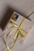 A gift parcel wrapped with Butter Cream Satin Ribbon, showing the soft pale yellow satin ribbon tied into a delicate bow for elegant packaging.
