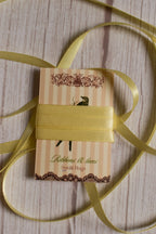 Butter Cream Satin Ribbon shown with loose pale yellow satin strands around the product card, suitable for crafts, packaging, gift styling, and decorative bows.