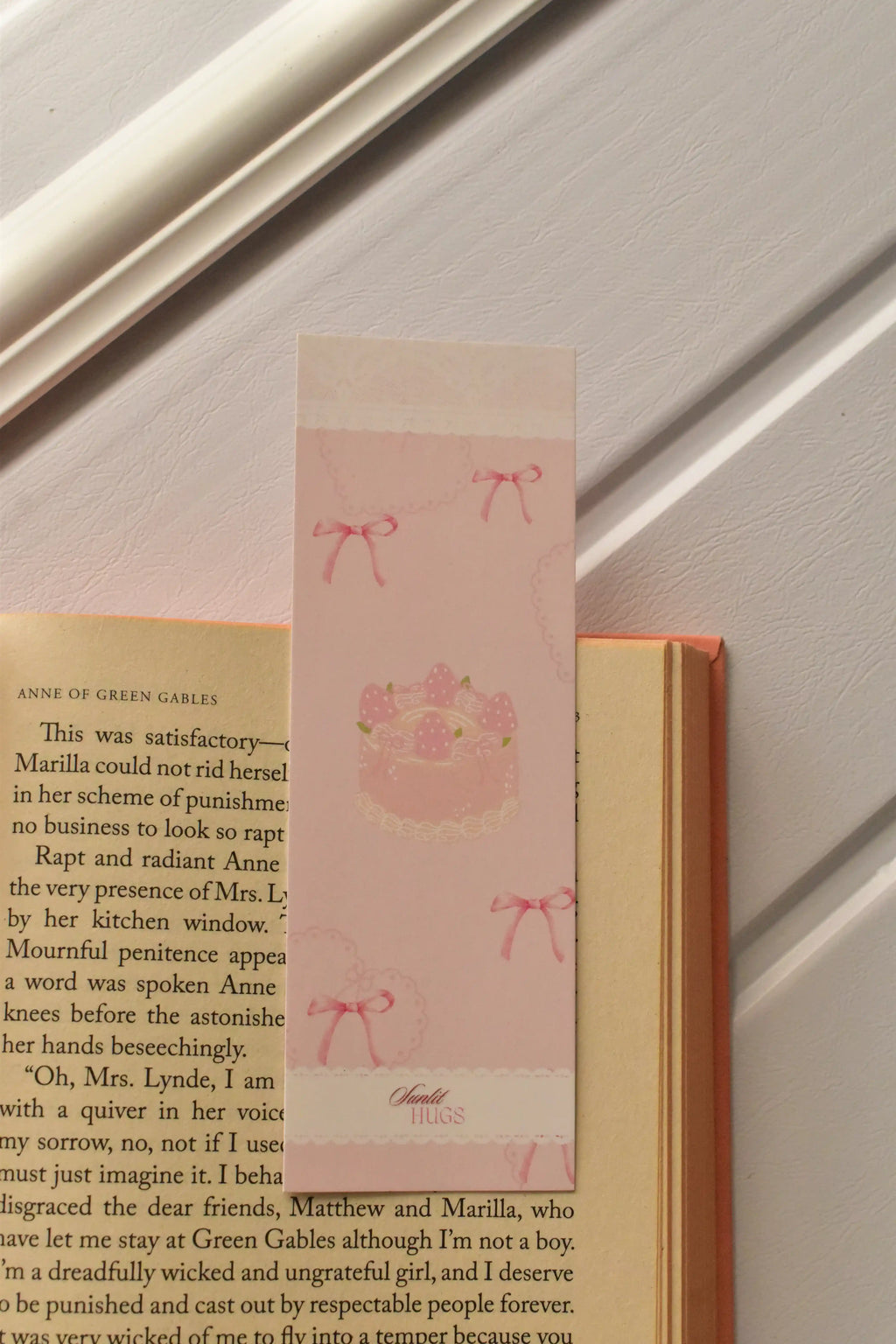 This warm shot demonstrates the bookmark in action, showing the strawberry cake design tucked inside a book, perfect for marking your place during a cosy, sweet reading moment.