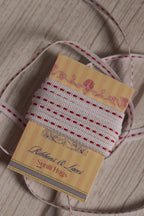 Candy Seam Narrow Ribbon shown with loose ribbon strands around the product card, highlighting its red and white stitched design for crafts, packaging, and bows.