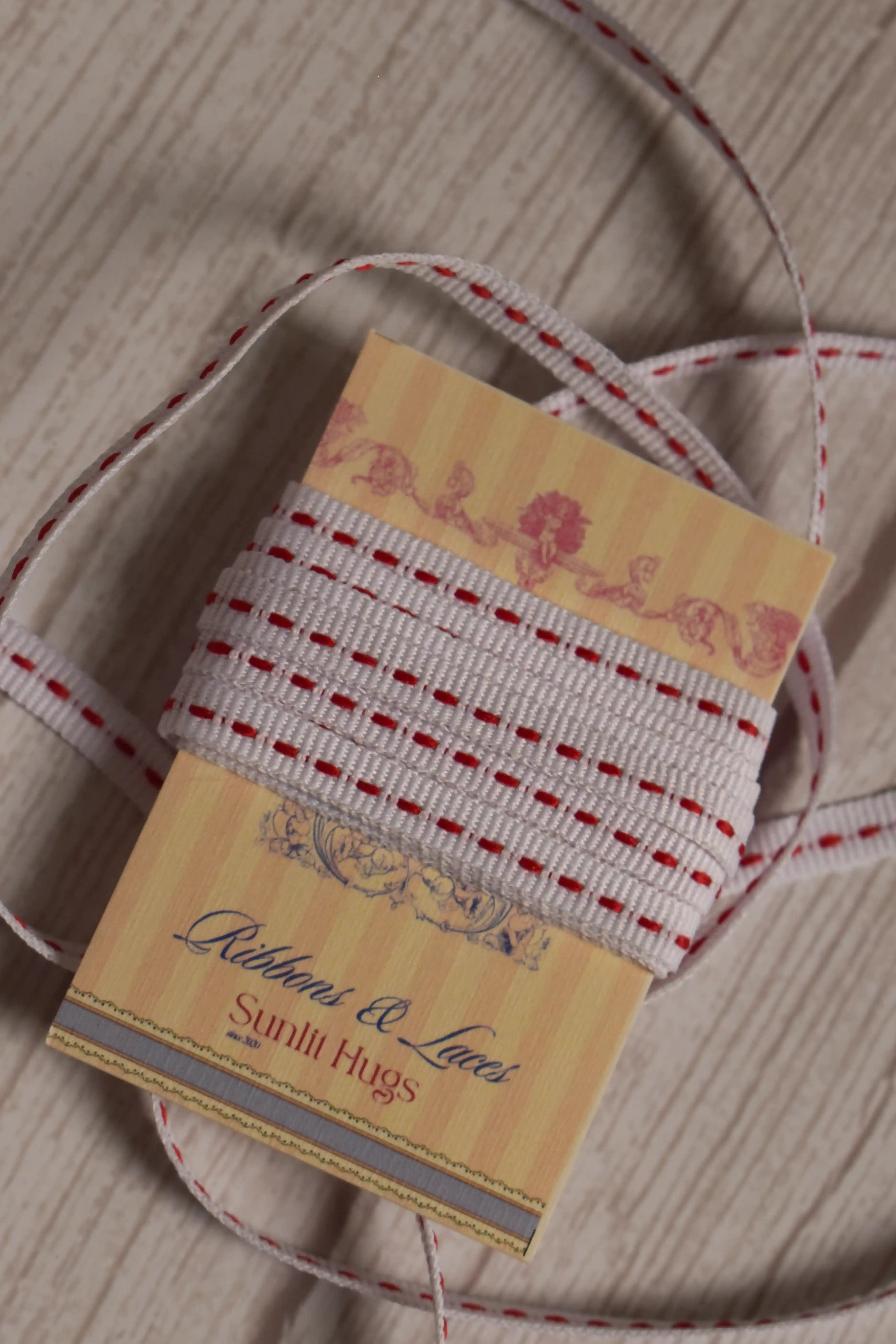 Candy Seam Narrow Ribbon shown with loose ribbon strands around the product card, highlighting its red and white stitched design for crafts, packaging, and bows.