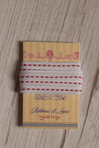Candy Seam Narrow Ribbon displayed on a Sunlit Hugs ribbon card, showing its white base, red stitched detailing, and narrow 6 mm width.