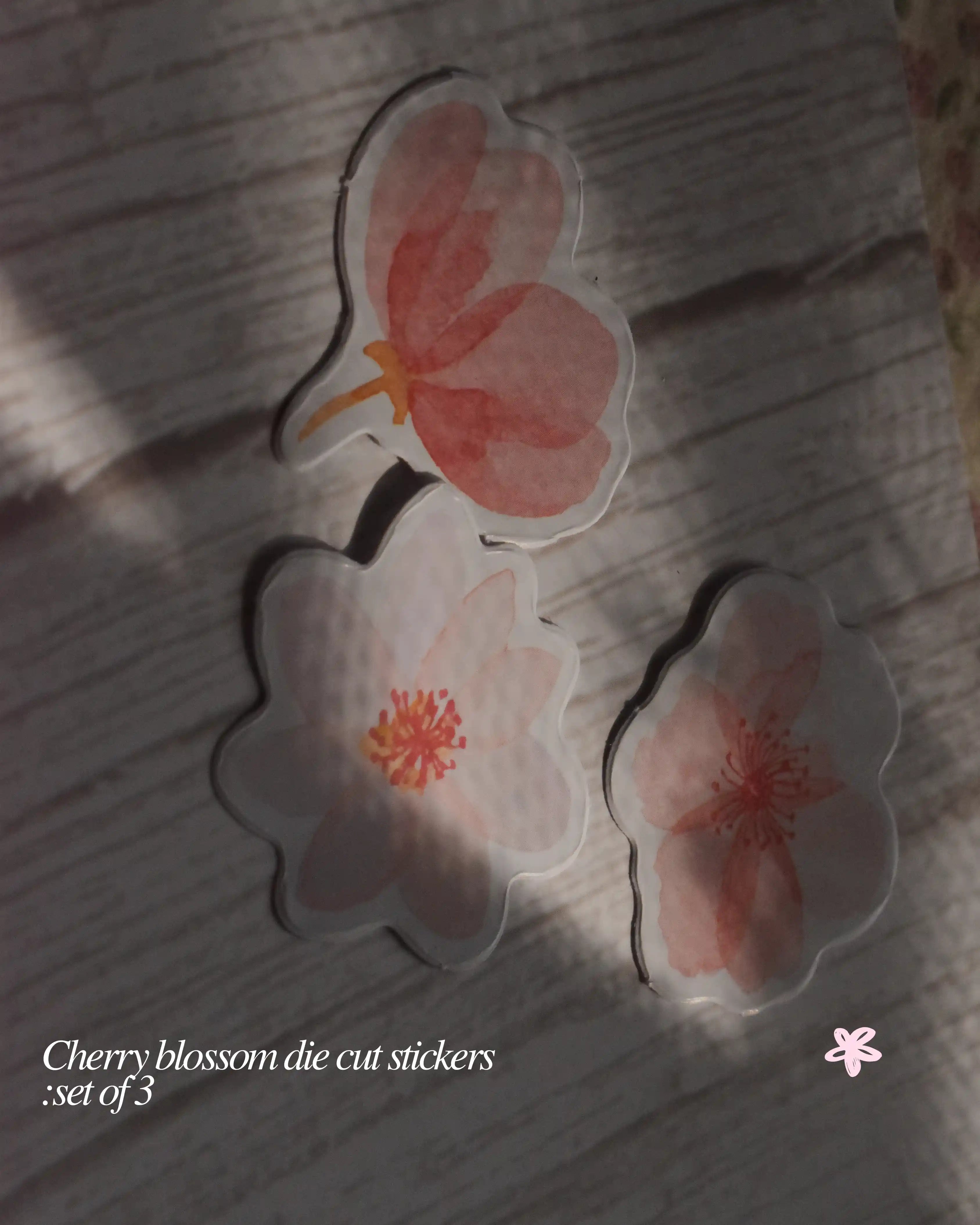Cherry blossom die cut stickers on a textured surface with text overlay.