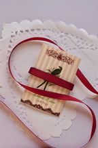 Narrow cherry red satin ribbon (6mm, 2 Metres) wrapped tightly across a "Sunlit Hugs" card, highlighting the sleek, smooth texture.
