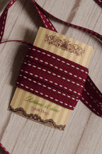 Cherry Stitches Ribbon shown with loose ribbon strands around the product card, highlighting its cherry red shade, white stitched detailing, and decorative finish.