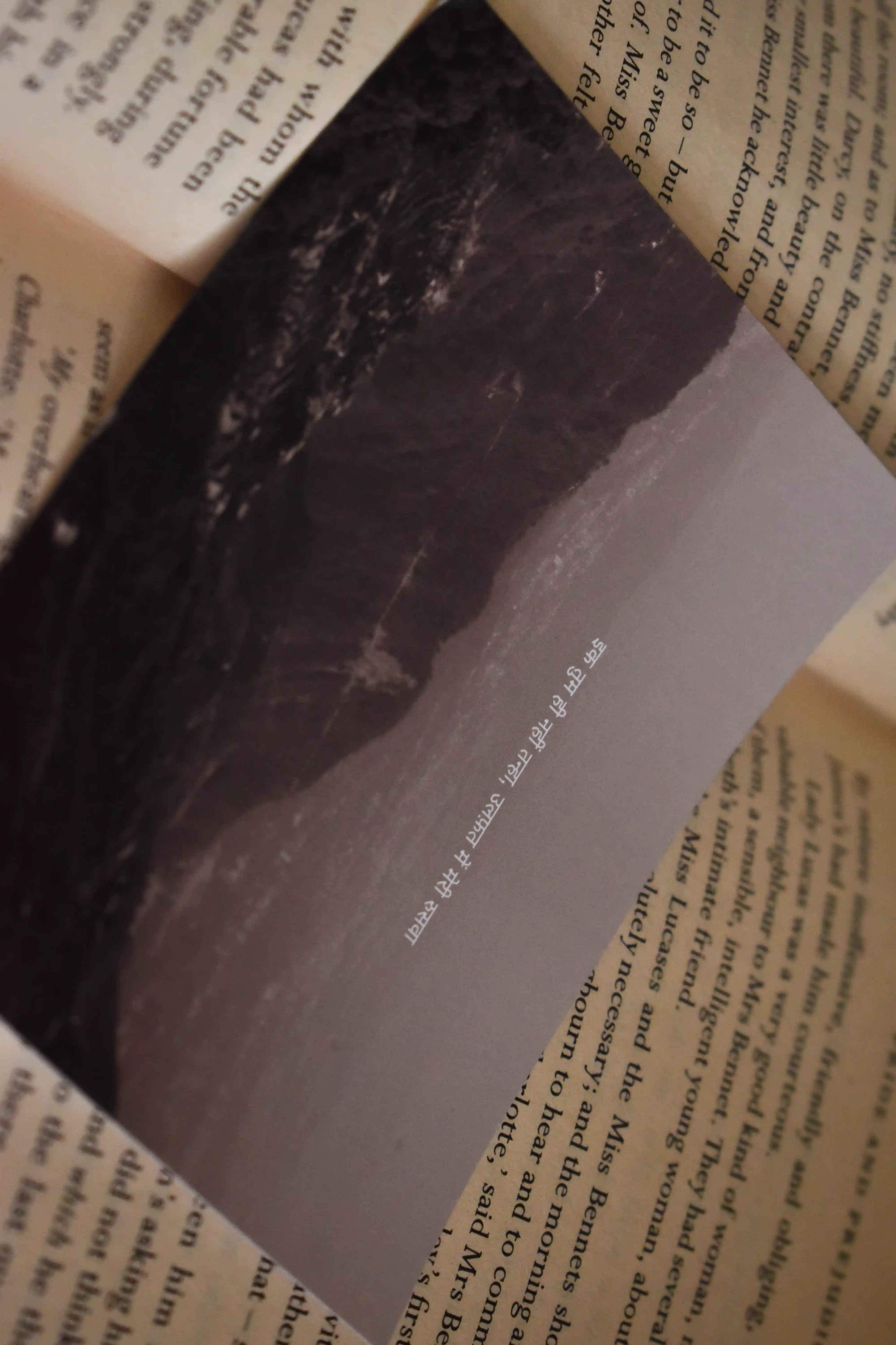 Macro detail shot of the 'Ek Tum Hi Nahi Tanha' Landour Photo Print resting on a book page, focusing on the dark mountain valleys and the poetic Hindi lyric text.