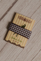 Cortado Checks Ribbon displayed on a Sunlit Hugs ribbon card, showing its coffee brown and white checked pattern for crafts, packaging, and bows.