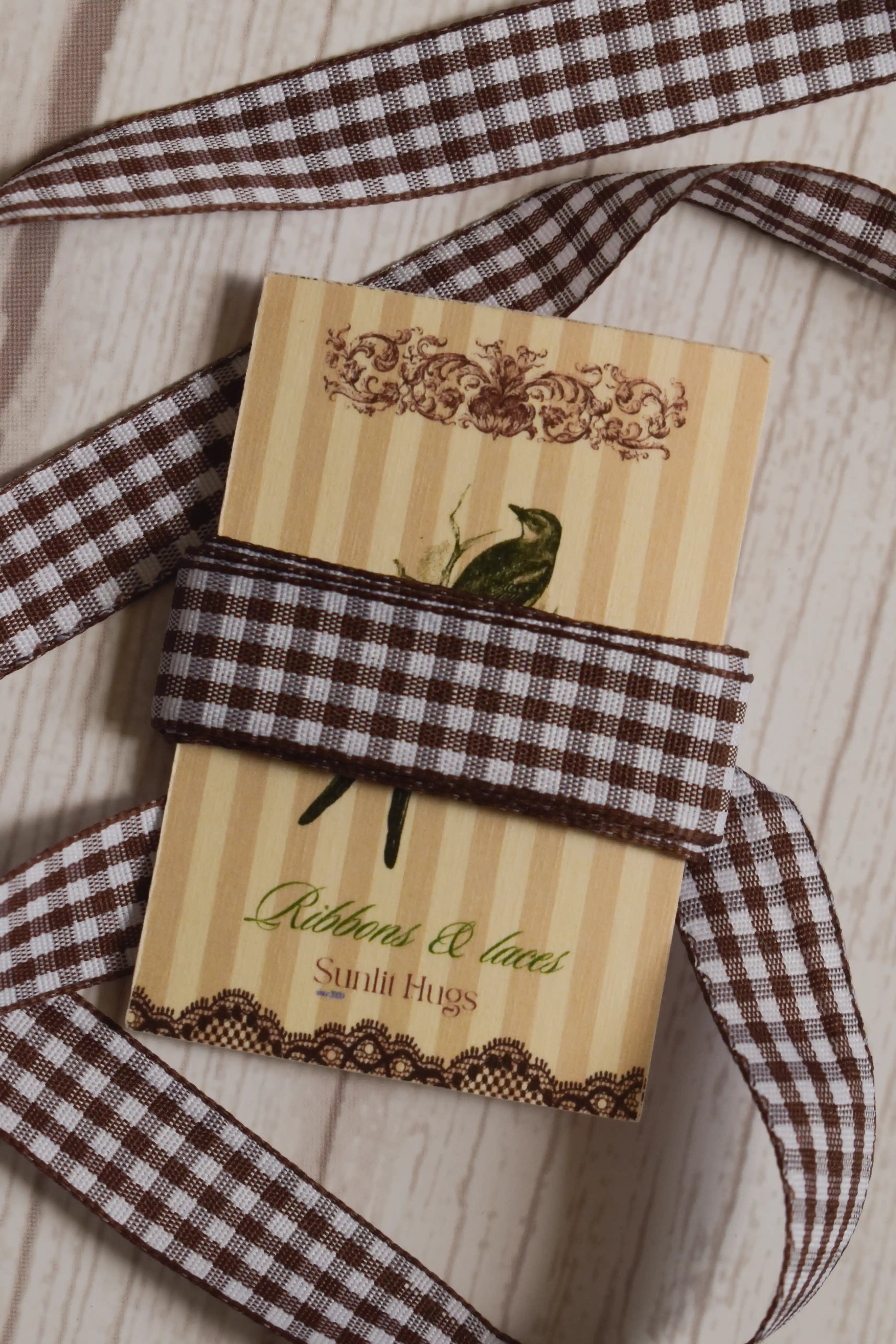 Cortado Checks Ribbon shown with loose brown and white checked ribbon strands around the product card, suitable for craft projects, packaging, scrapbooking, and decorative bows.