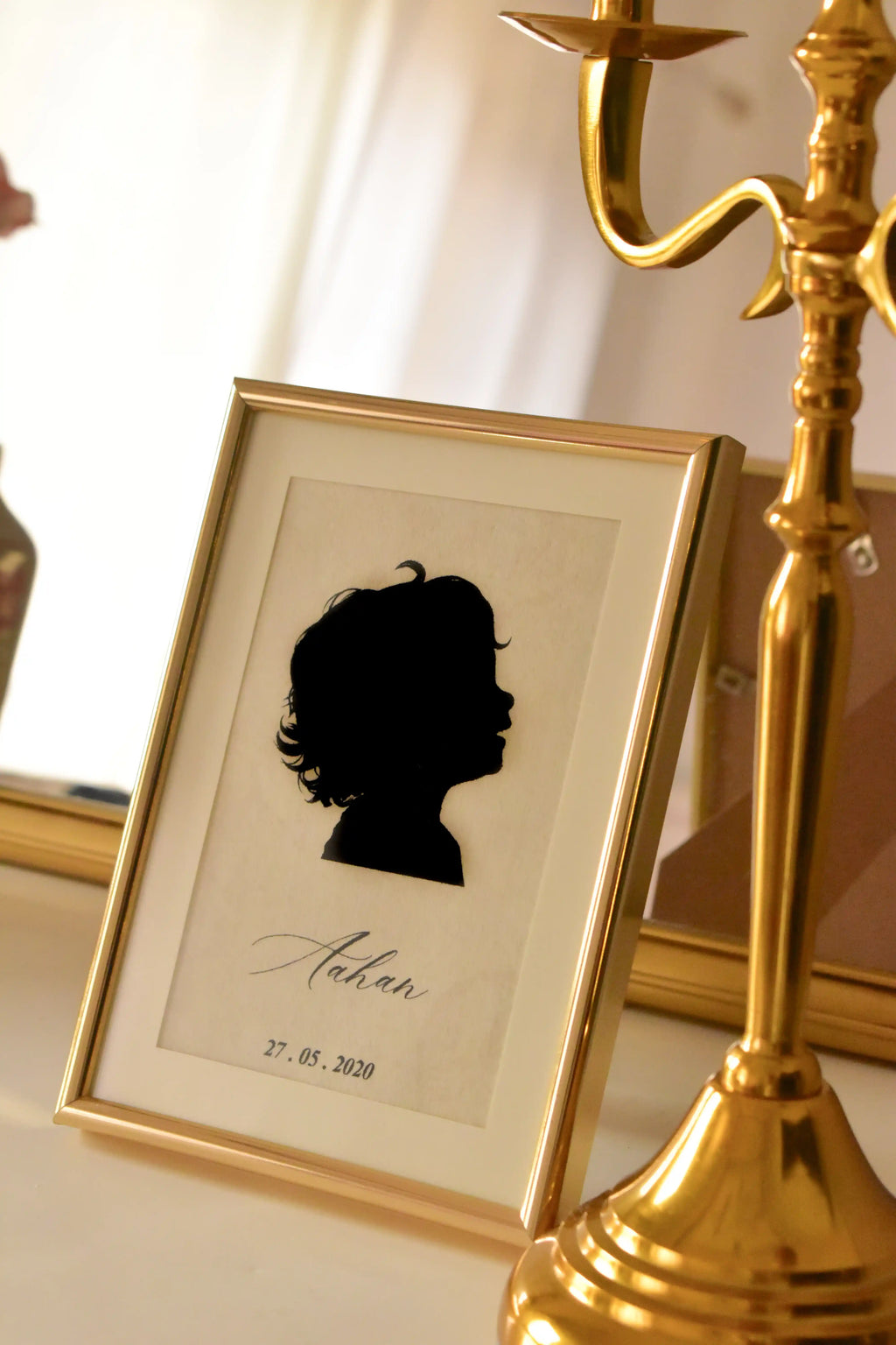 This lifestyle shot captures the silhouette of 'Aahan' in a warm setting, illustrating how the golden frame and vintage aesthetic blend beautifully with existing home décor.