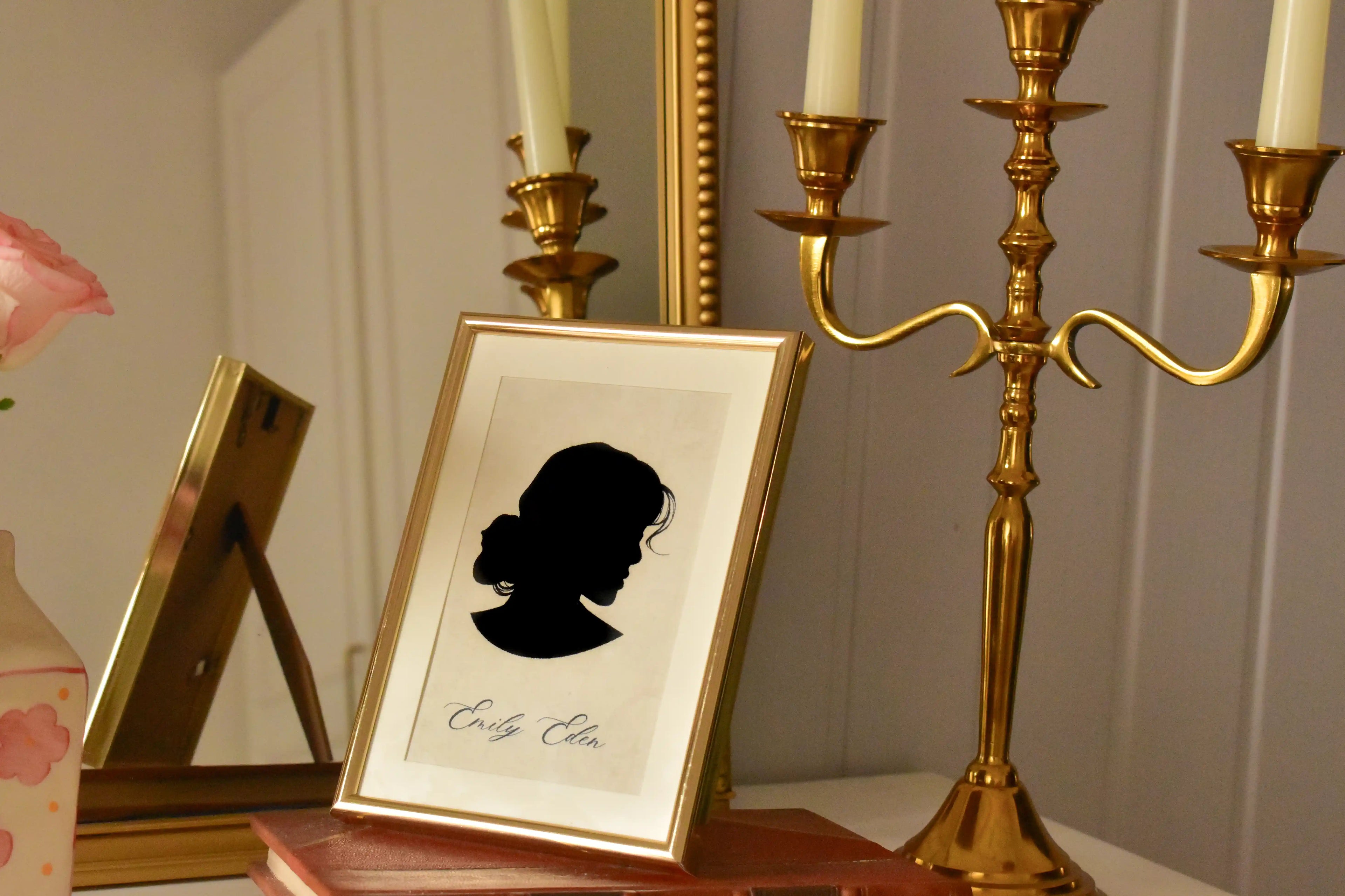 A view of the Emily Eden silhouette portrait in a dimmer, intimate light, demonstrating how the golden frame beautifully catches the light, making it a warm focal point in any room.
