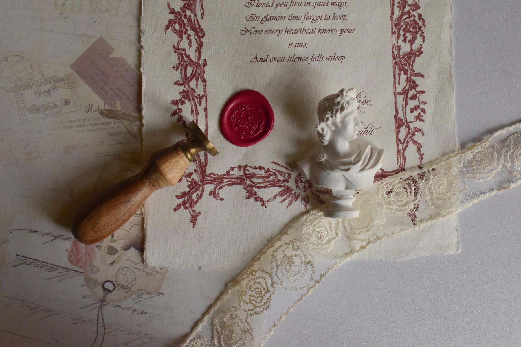 Decorative letter with wax seal, wooden stamp, and small statue on textured surface