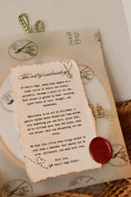 Hand embroidered hoop wrapped in Sunlit Hugs branded vellum paper, sealed with a red wax seal, and tied with a green gingham ribbon.