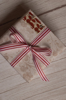 A vintage-style gift parcel tied with Cheese Tomato Stripes Ribbon, showing the red and light striped ribbon styled as a bow for thoughtful packaging.
