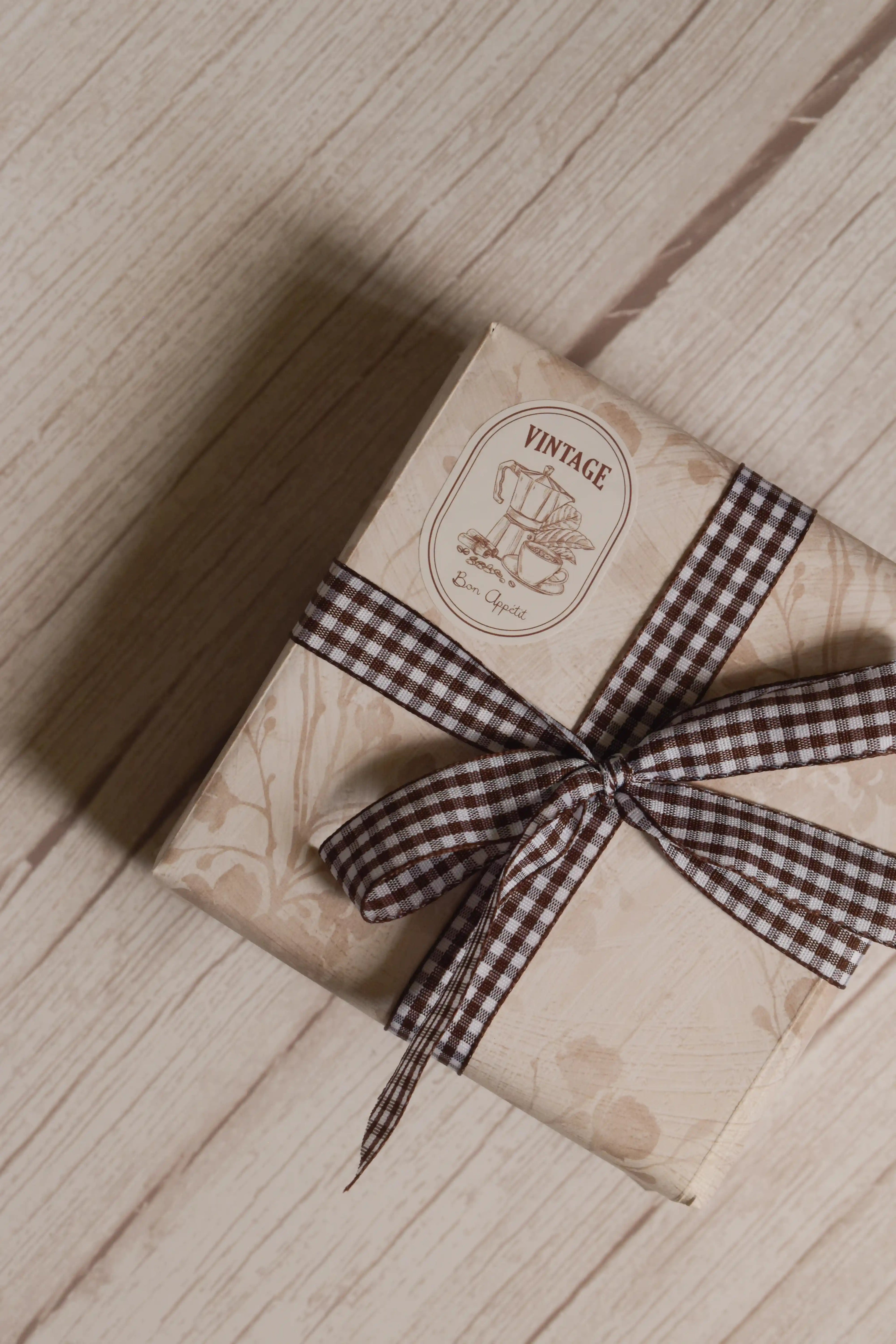 A vintage-style gift parcel tied with Cortado Checks Ribbon, showing the brown and white checked ribbon styled as a bow for warm and thoughtful packaging.
