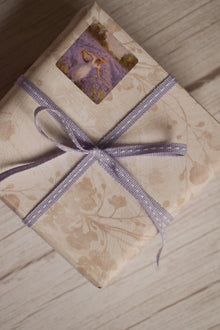 A vintage-style gift parcel tied with Lilac Stitches Narrow Ribbon, showing the soft lilac purple ribbon styled as a delicate bow for thoughtful packaging.