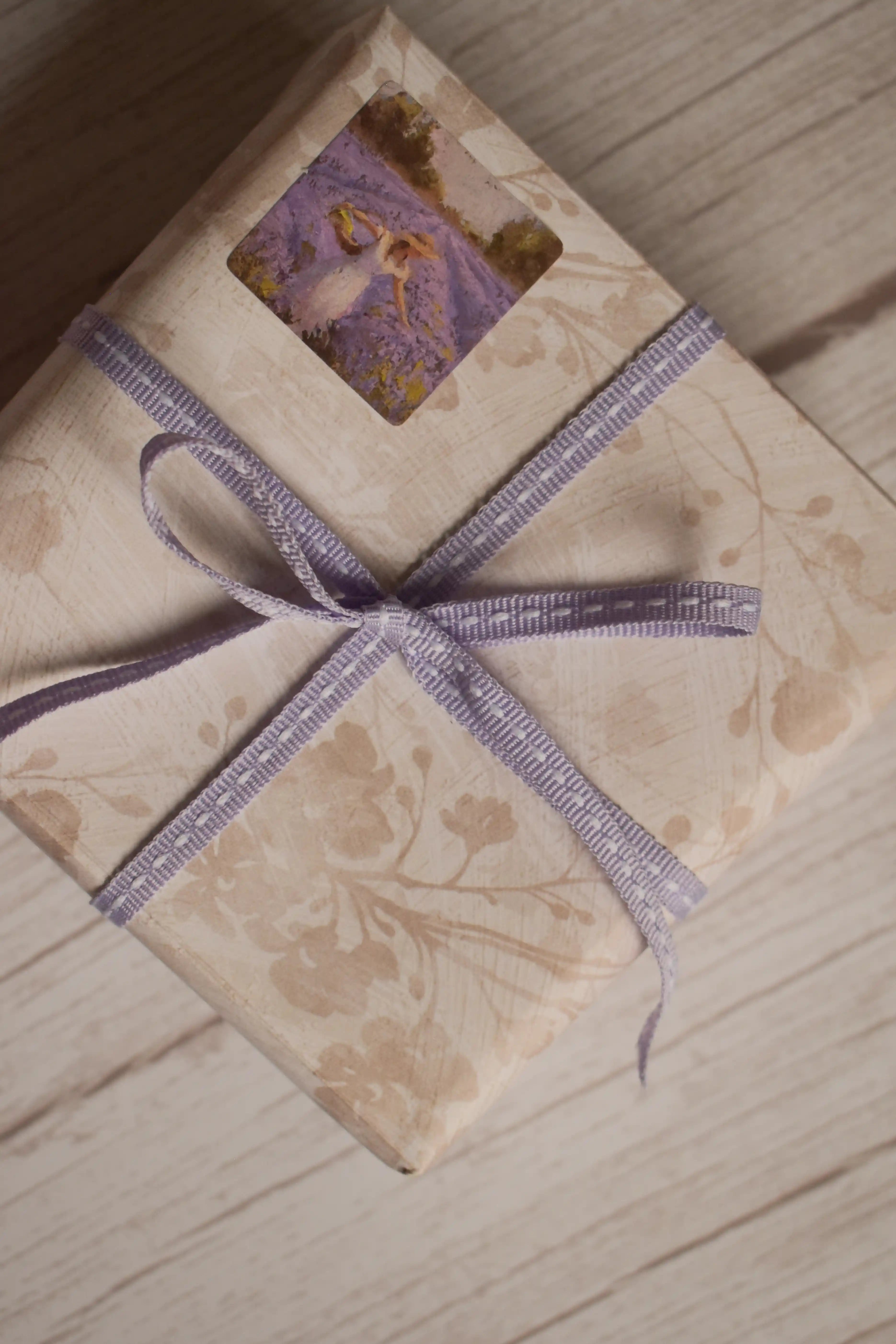 A vintage-style gift parcel tied with Lilac Stitches Narrow Ribbon, showing the soft lilac purple ribbon styled as a delicate bow for thoughtful packaging.