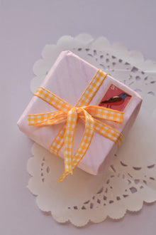A small gift parcel tied with Mango Gingham Checkered Ribbon, showing the yellow and white checkered ribbon styled as a cheerful bow for thoughtful packaging.