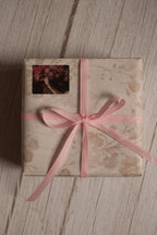 A vintage-style gift parcel tied with Petal Silk Ribbon, showing the soft pink ribbon styled as a delicate bow for thoughtful packaging.