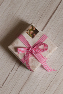 A vintage-style gift parcel tied with Rose Picnic Ribbon, showing the pink and white checked ribbon styled as a cheerful bow for thoughtful packaging.
