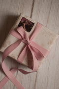 A vintage-style gift parcel tied with a blush pink grain ribbon bow, showing how the ribbon can be used for soft and elegant gift packaging.