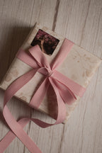 A vintage-style gift parcel tied with a blush pink grain ribbon bow, showing how the ribbon can be used for soft and elegant gift packaging.