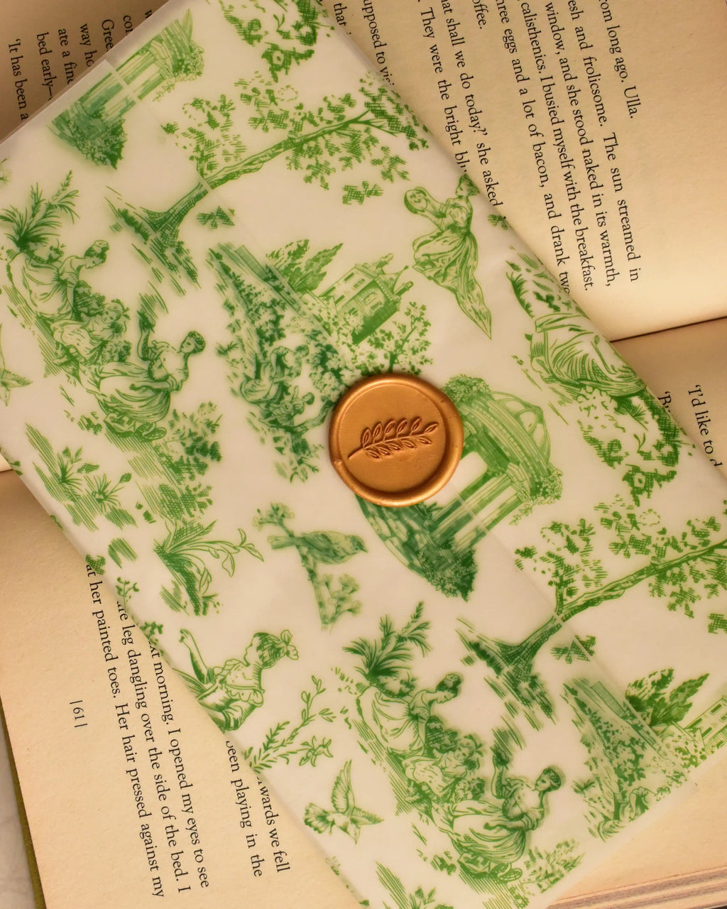 A detailed view highlighting the rich golden wax seal and its delicate leaf design, showcasing the meticulous craftsmanship over the green toile architectural print.