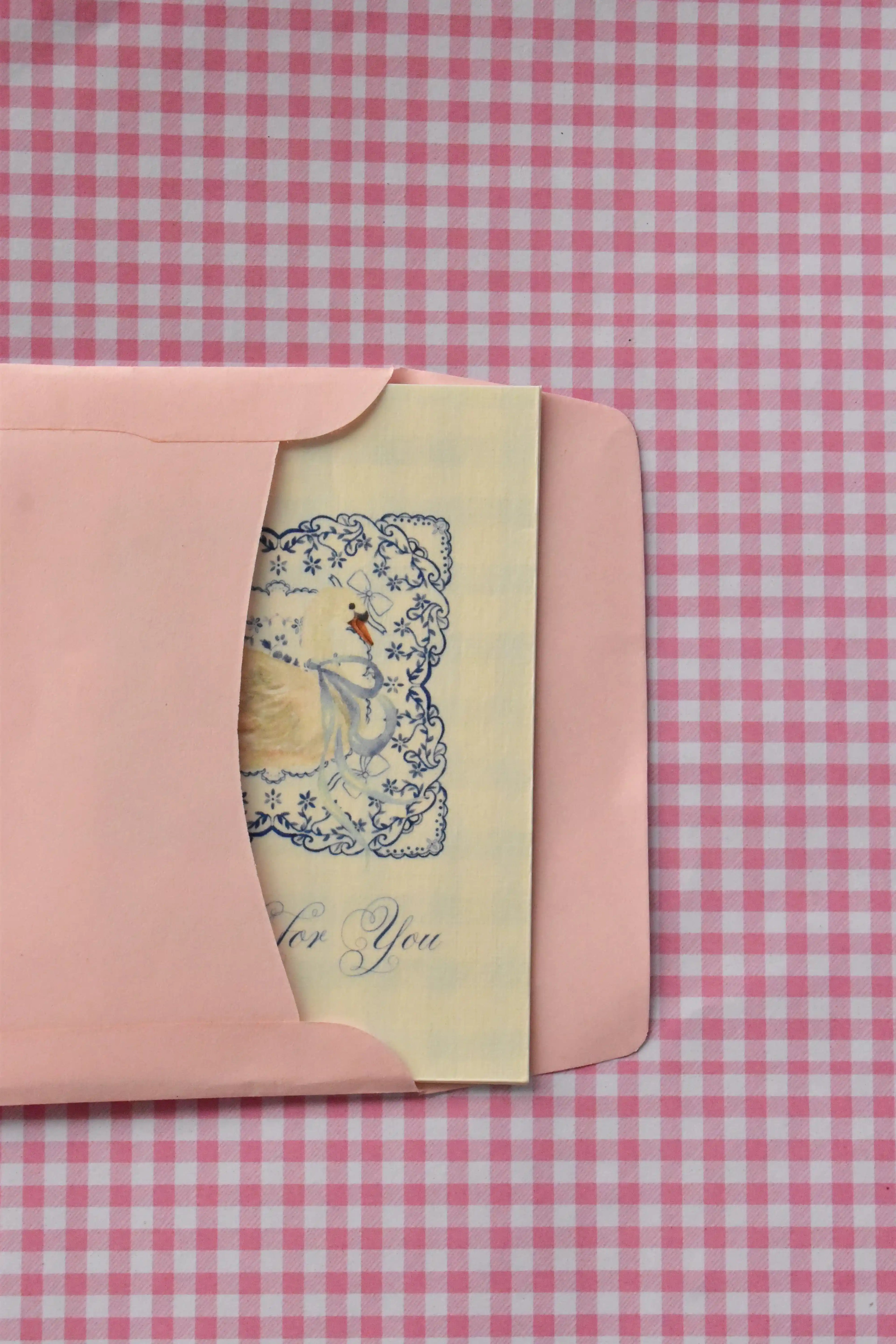This view captures the beginning of the card's journey, showing the Grateful For You card, with its beautiful blue design, being placed into the pink envelope, ready to be sent as a warm gesture of thanks.
