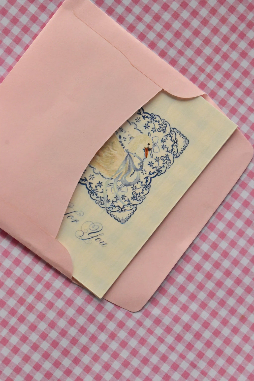 This image offers an edge-on view of the Grateful For You card nestled inside the pink envelope, highlighting the subtle beauty of the card's cream colour and blue lace design as it awaits sealing.