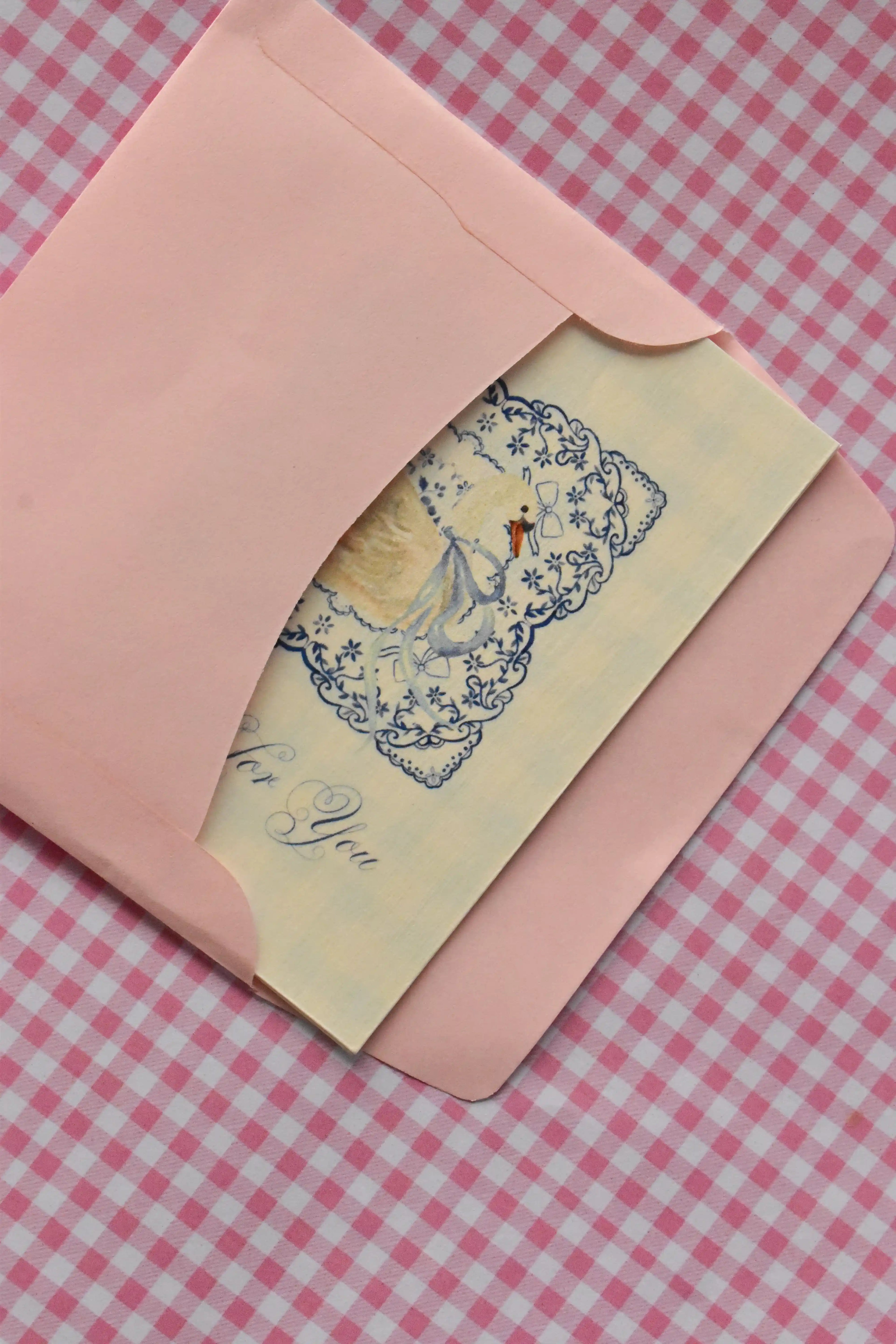 This image offers an edge-on view of the Grateful For You card nestled inside the pink envelope, highlighting the subtle beauty of the card's cream colour and blue lace design as it awaits sealing.