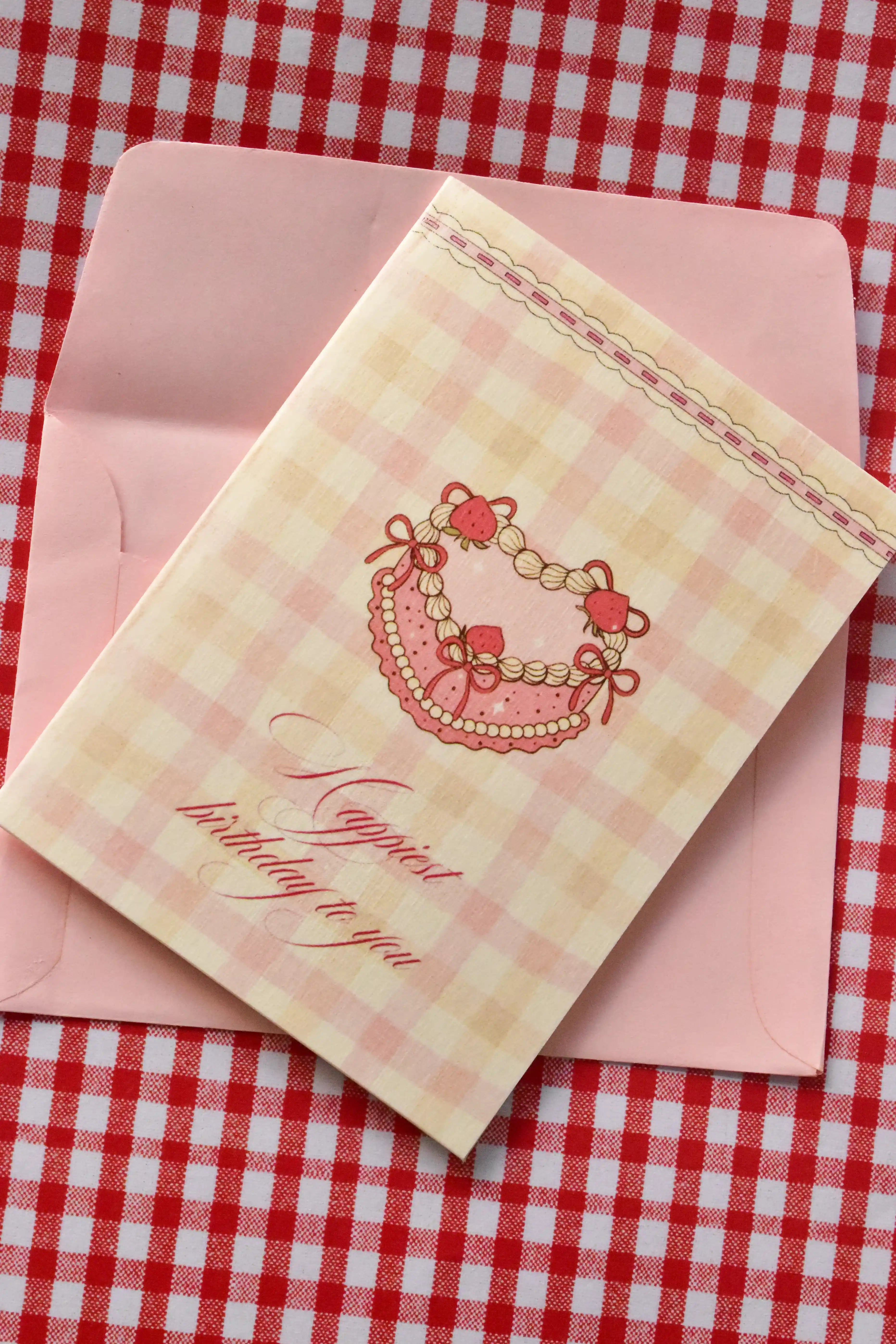 This detailed shot focuses on the main heart-shaped cake design and the message, clearly showing the quality of the textured paper and the soft pink colours of the illustration.