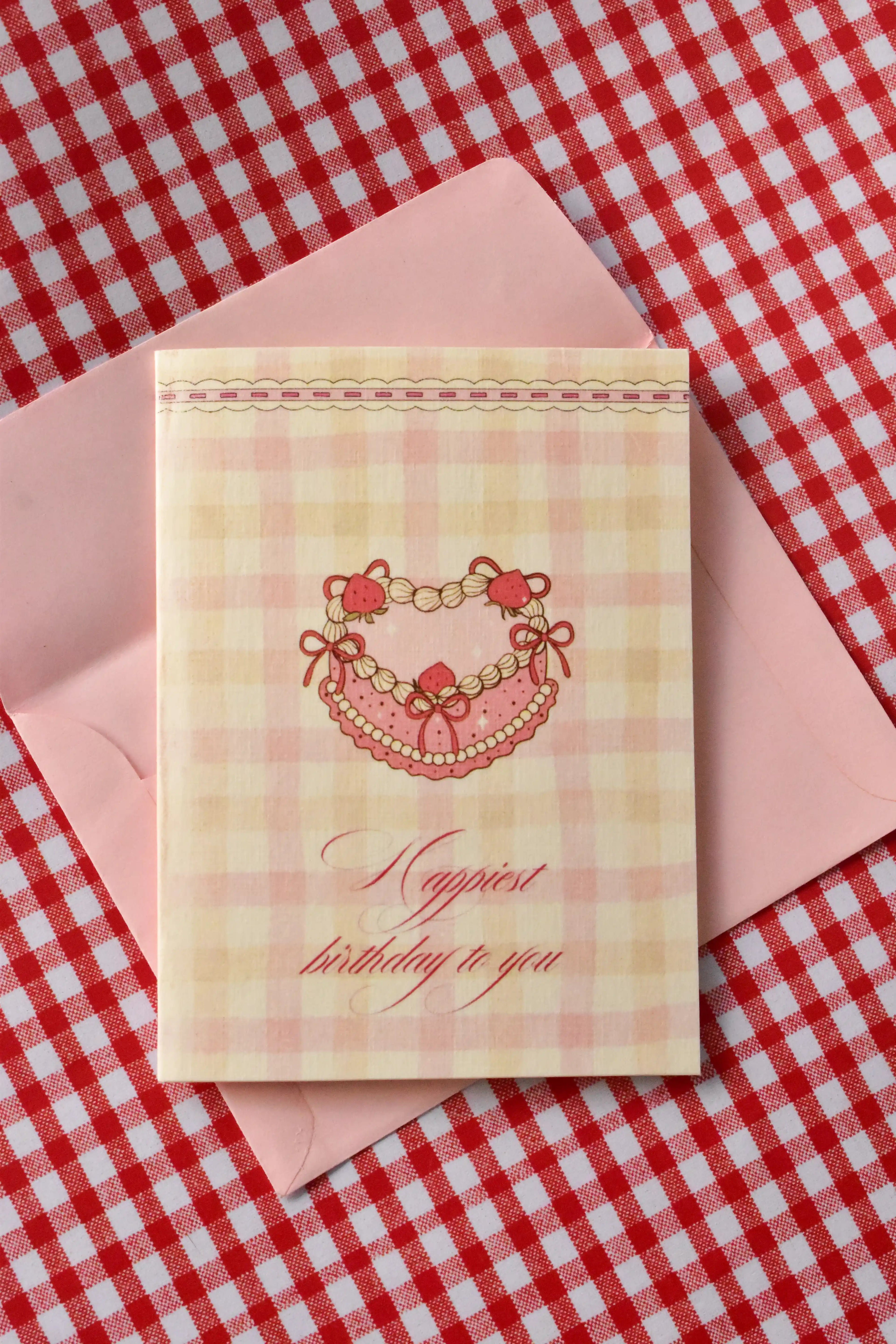 This image shows the front of the 'Happiest Birthday to You' card, featuring the nostalgic strawberry heart cake design and pink and cream gingham pattern from the set.