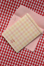 This image displays the back of the 'Happiest Birthday To You' card, highlighting the soft pink and cream gingham design and the Sunlit Hugs logo.