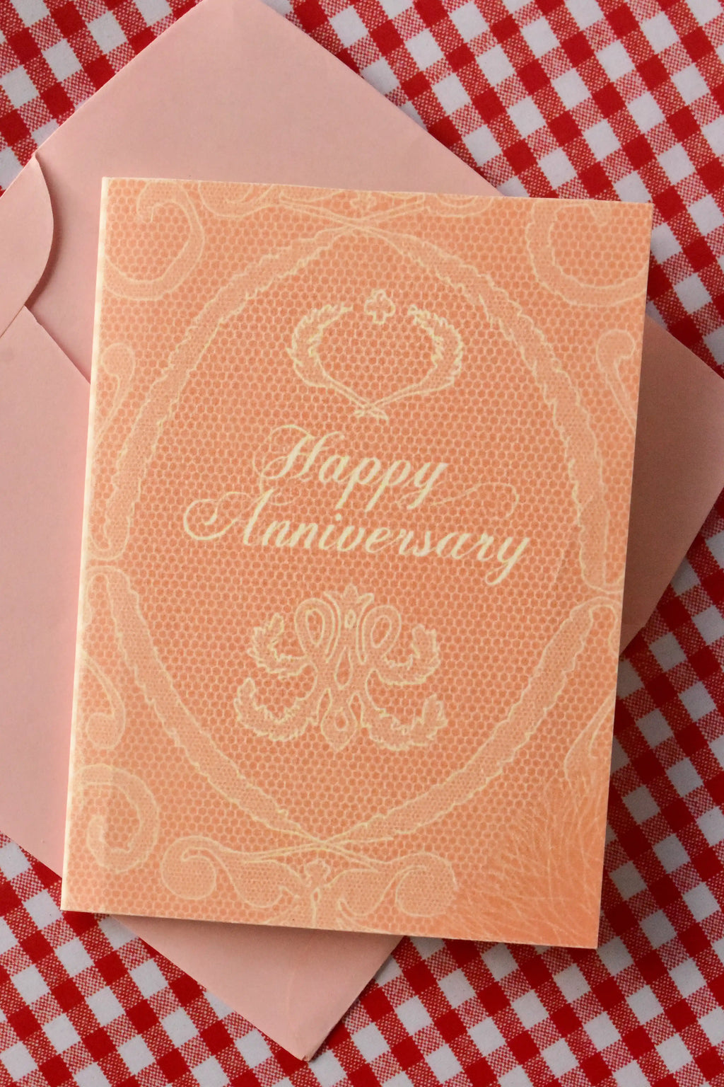 This beautiful image showcases the Happy Anniversary card in full, highlighting the elegant peach colour and the delicate, intricate white lace design that speaks of a timeless love story.
