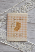 Full front view of the Sunlit Hugs Happy Birthday Sock Twin Greeting Card showing floral socks on a beige gingham background with lace edges.