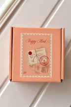 This image showcases the thoughtful 'Happy Mail' packaging, confirming that the bookmarks will arrive in a charming peach-coloured box with a vintage-style stamp.