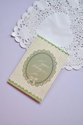 Vintage style happy birthday card with green and white stripes, featuring a scalloped oval frame and a small bow illustration.