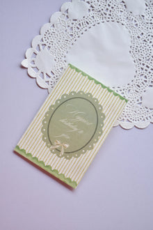 Vintage style happy birthday card with green and white stripes, featuring a scalloped oval frame and a small bow illustration.