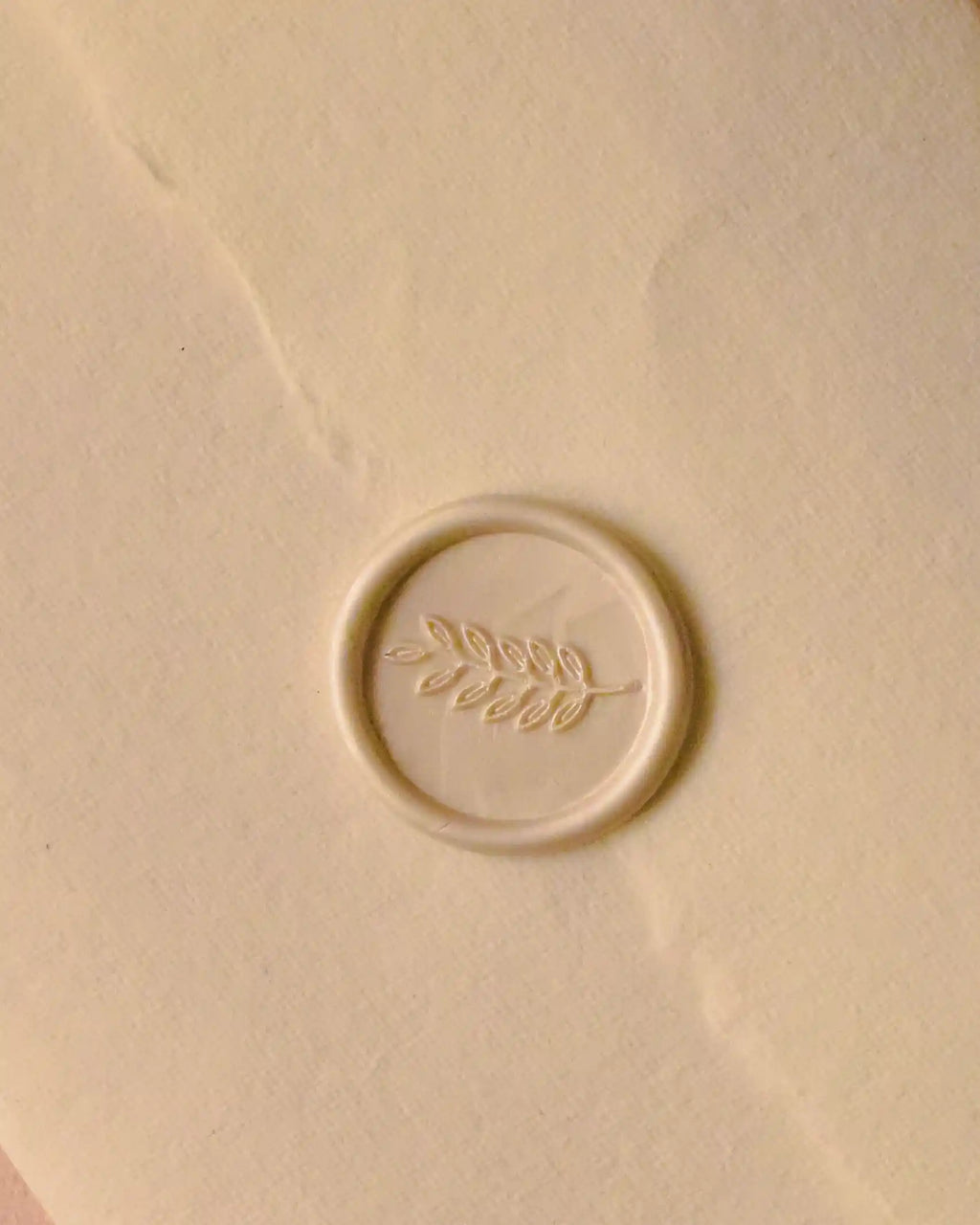 A detailed view showcasing the final, elegant touch—the ivory wax seal with its graceful leaf design, which seals the old-world letter with class.