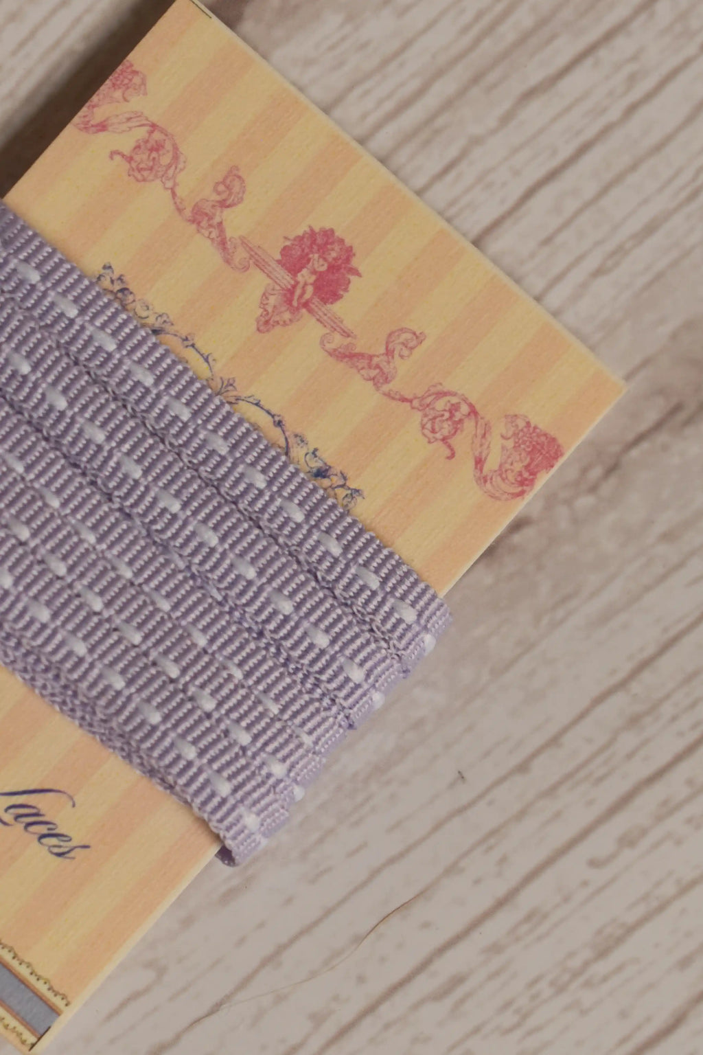 Close-up of Lilac Stitches Narrow Ribbon displayed on a Sunlit Hugs ribbon card, showing its soft lilac purple colour and white stitch-style detailing.