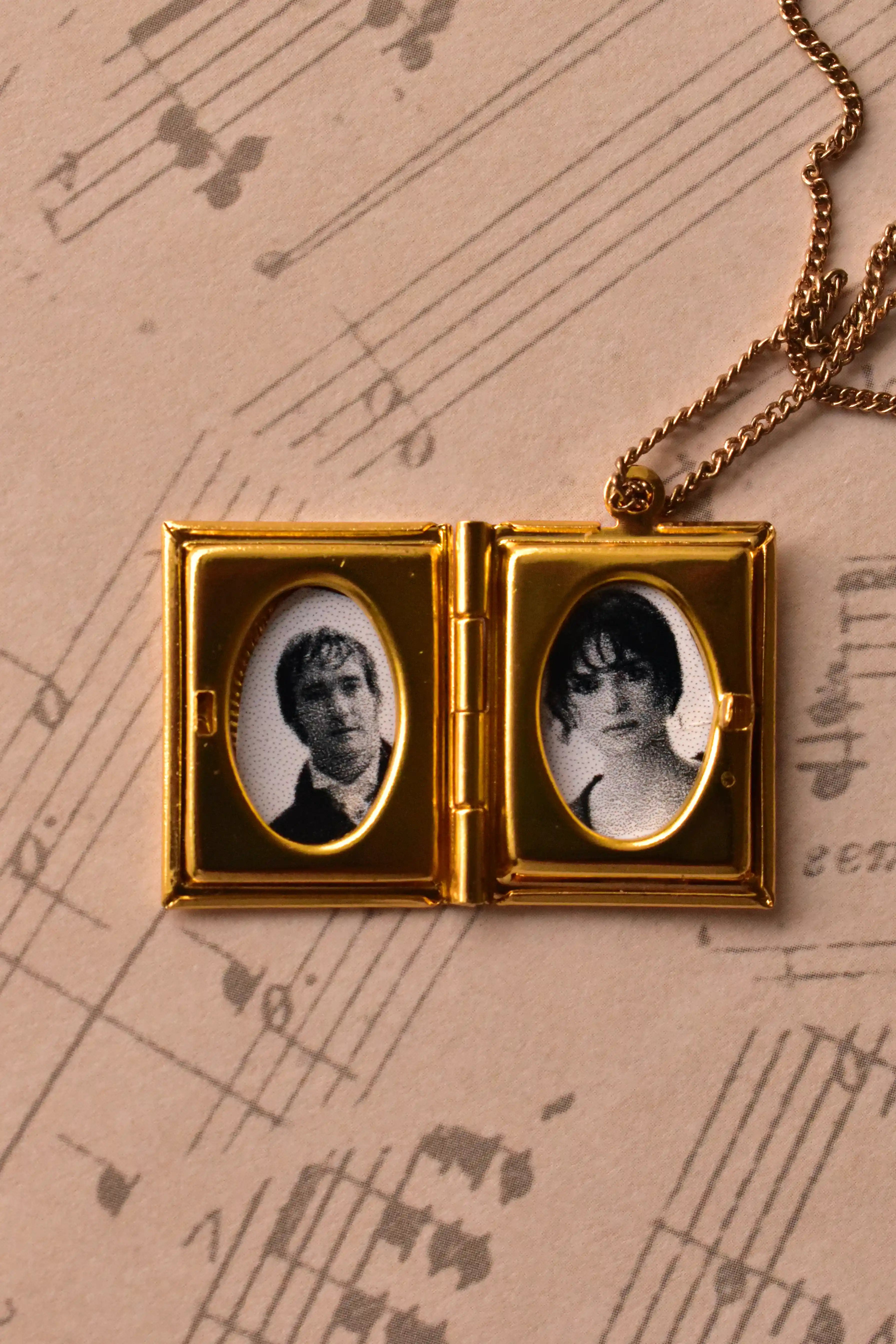 This angled image captures the open golden alloy locket, demonstrating how beautifully the black and white photos sit within the vintage frames. (Note: Chain is for visual purposes only).