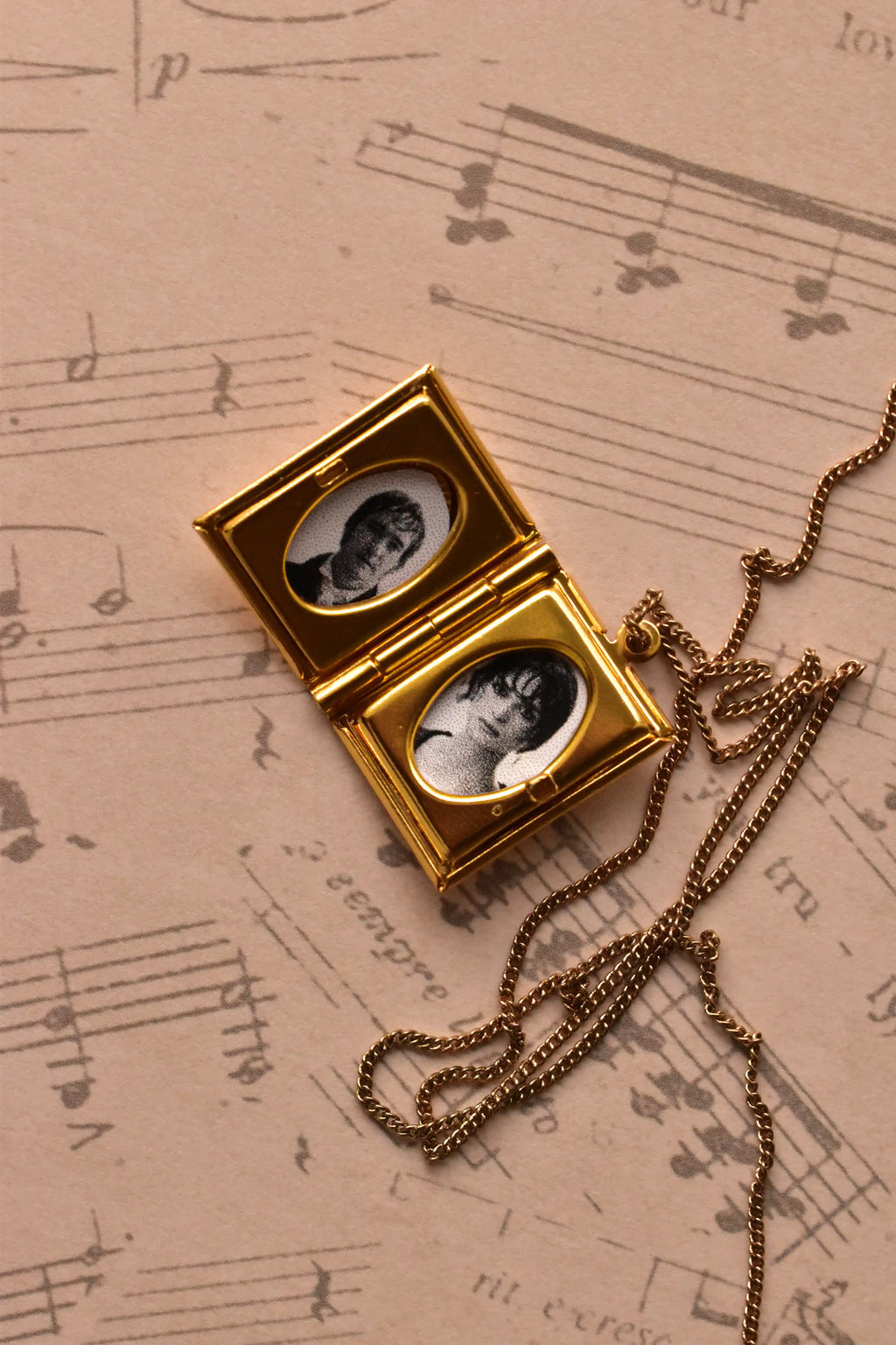 A detailed view of the open golden alloy locket, showcasing the quality of the two custom inserted black and white photographs, ready to preserve a precious moment.