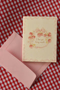 This image showcases the front of the Love You Berry Much card, highlighting the sweet strawberry wreath, bow, and flower motif and the soft, warm cream colour of the card, ready to share a heartfelt message.